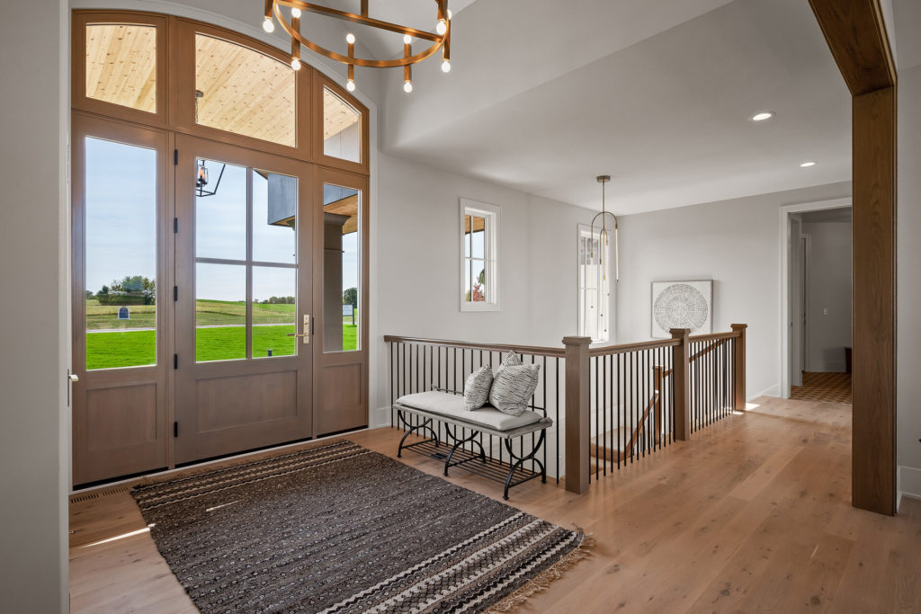 The entryway of a prairie transitional custom home has a wooden floor and a glass door.