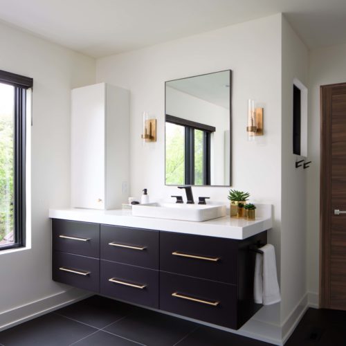 A modern black and white bathroom with a sink and mirror, undergoing a remodel.