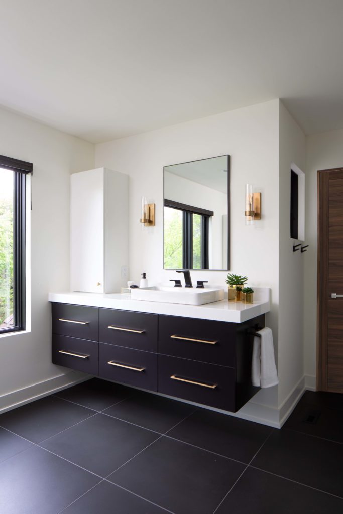 A modern black and white bathroom with a sink and mirror, undergoing a remodel.