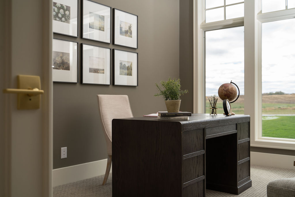 A prairie transitional custom home office with a desk, chair, and window.