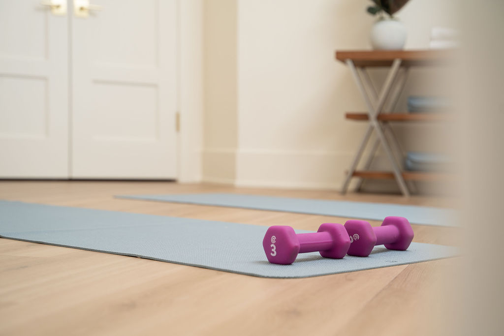 Two purple dumbbells on a mat in front of a prairie transitional custom home.