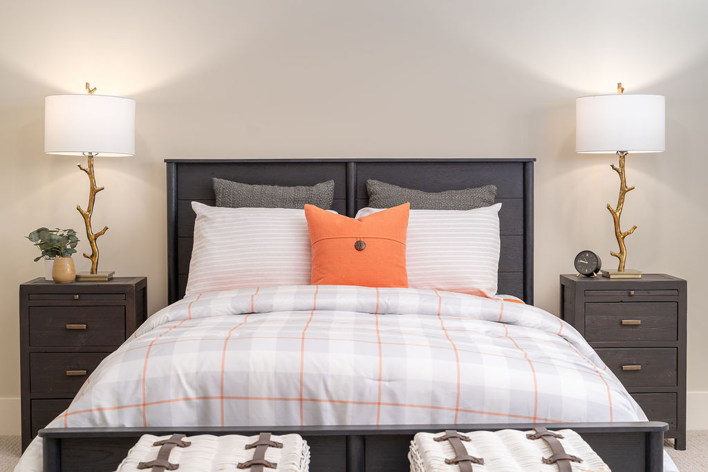 A prairie transitional custom home bedroom with a gray bed and orange pillows.