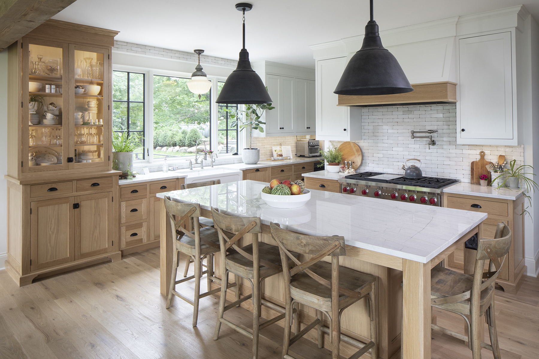 A prairie-style kitchen with a large island and wooden chairs in a custom home.