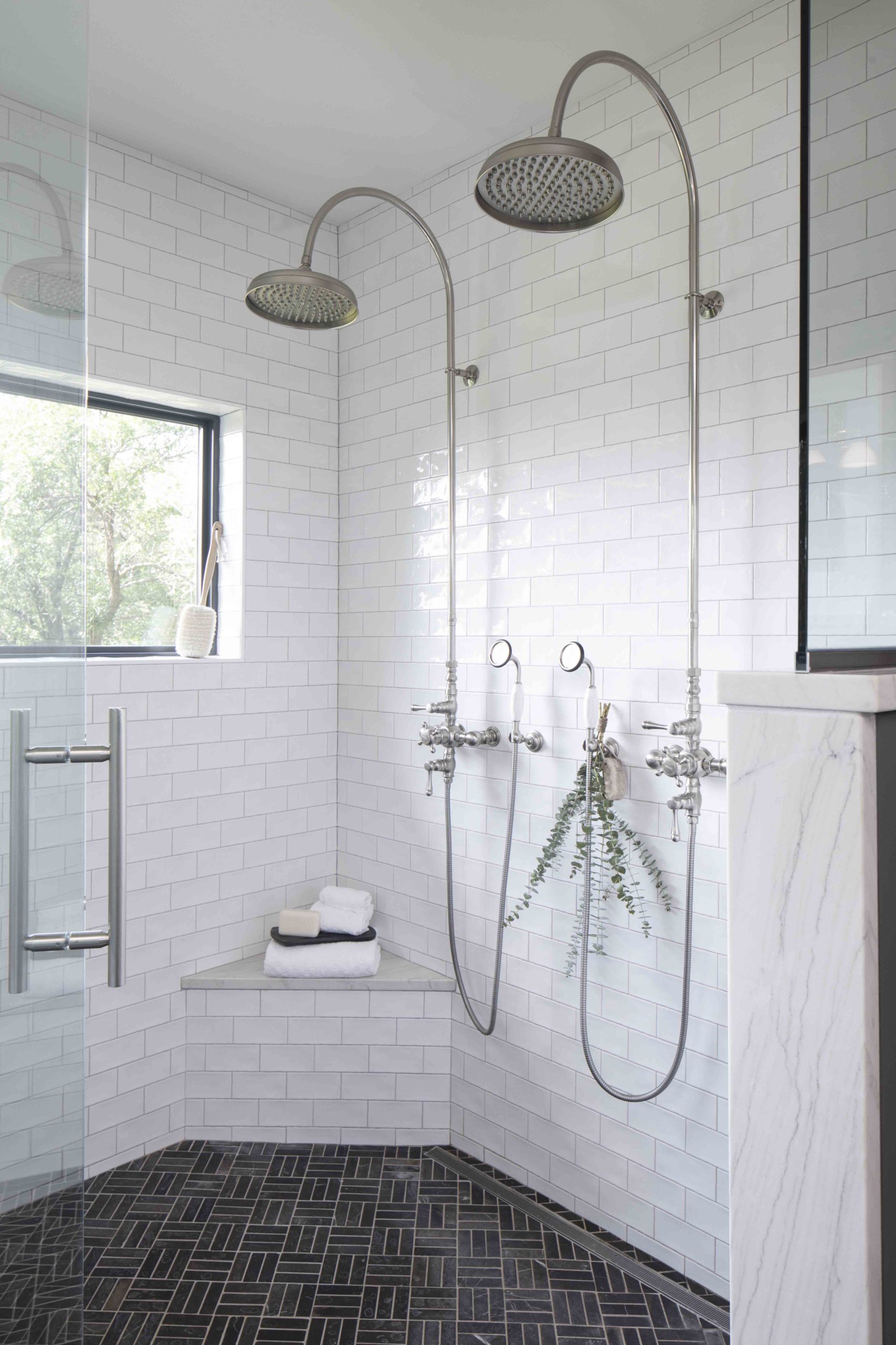 A white tiled bathroom with a glass shower stall in a prairie transitional custom home.