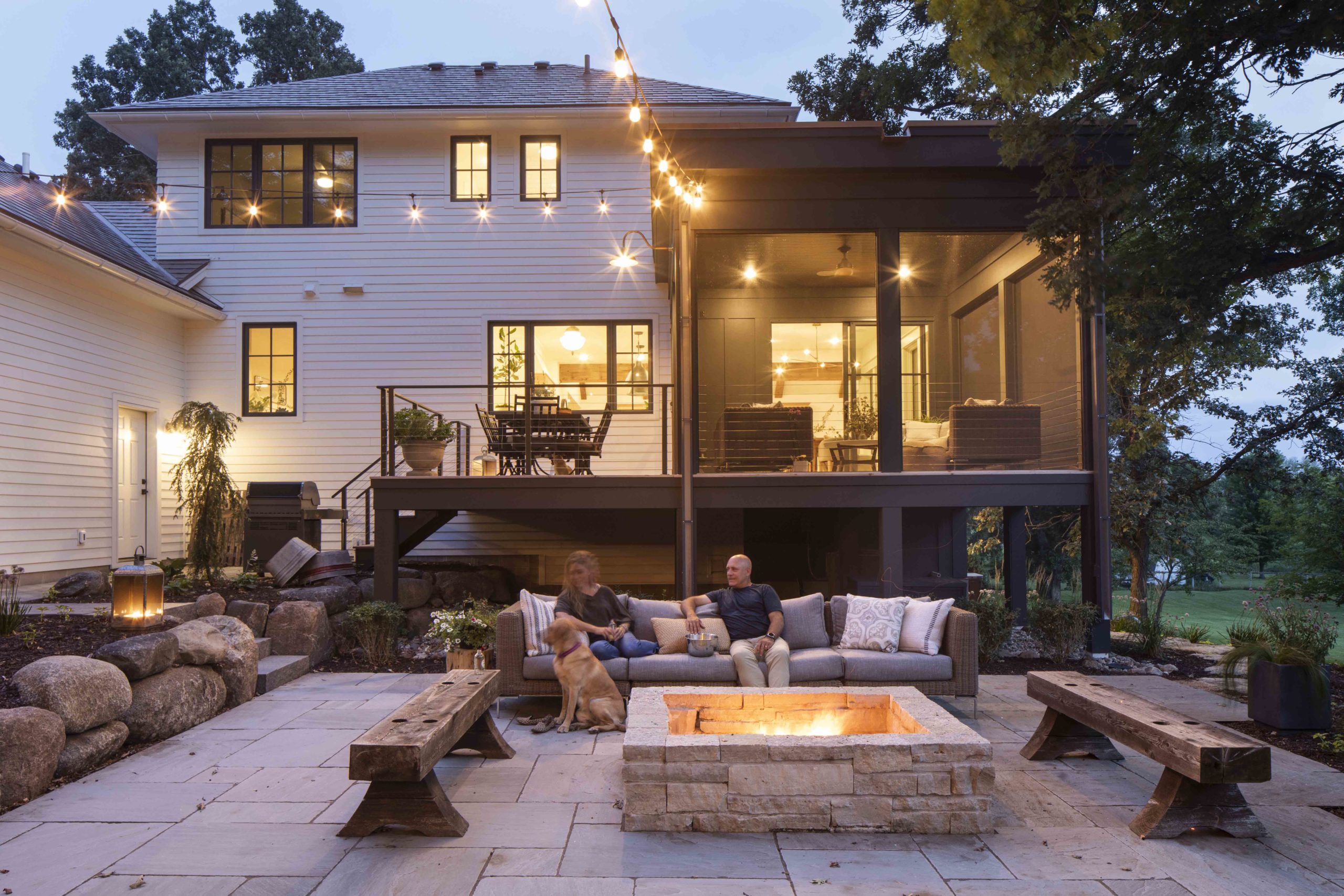 A couple enjoys the cozy ambiance of a fire pit in their backyard of a custom home.