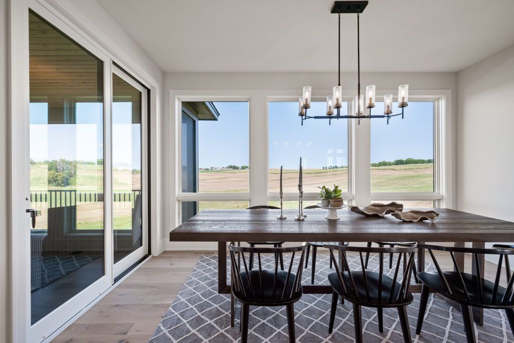 A prairie dining room with large windows overlooking a field.