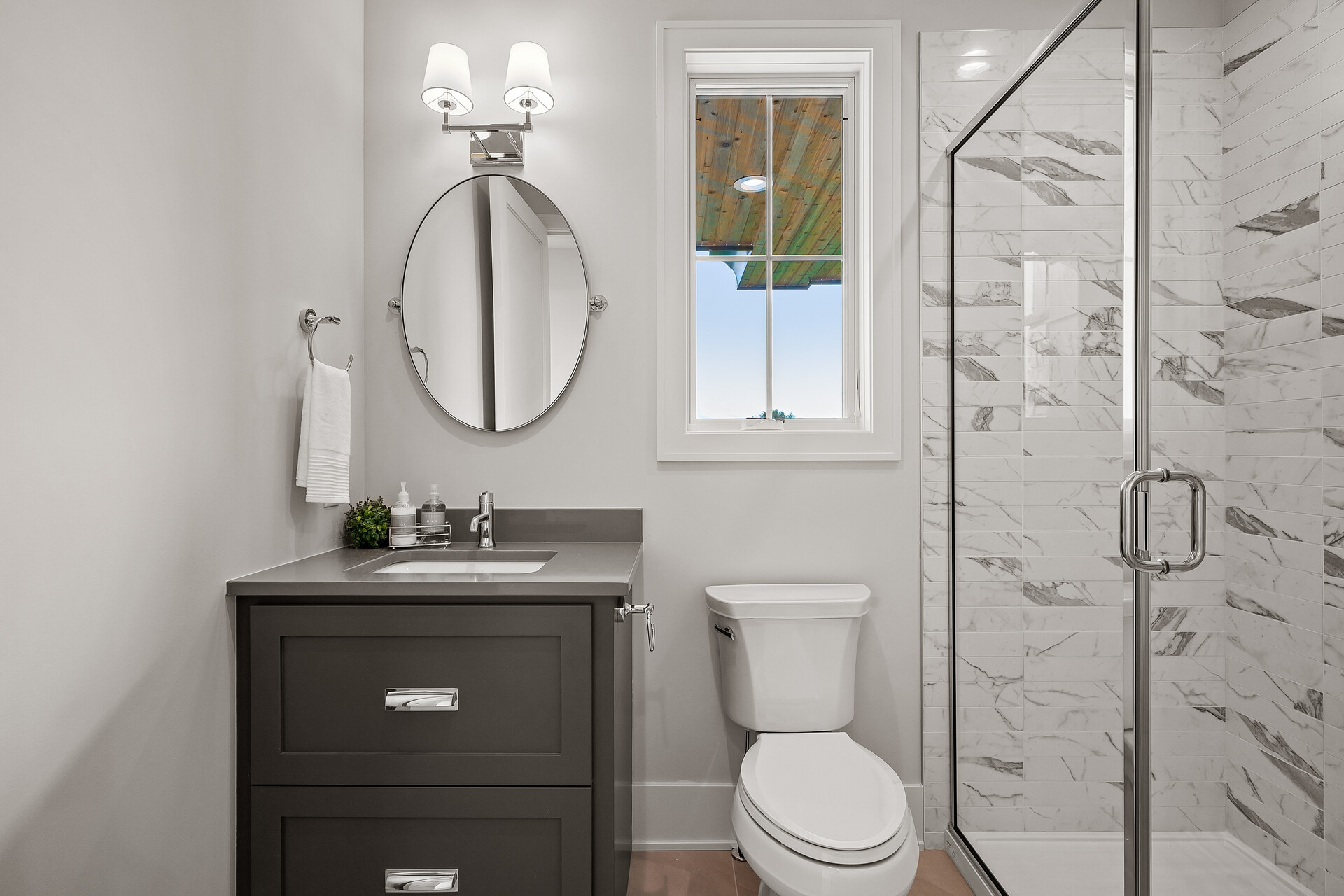 A prairie transitional bathroom with a toilet, sink and shower in a custom home.