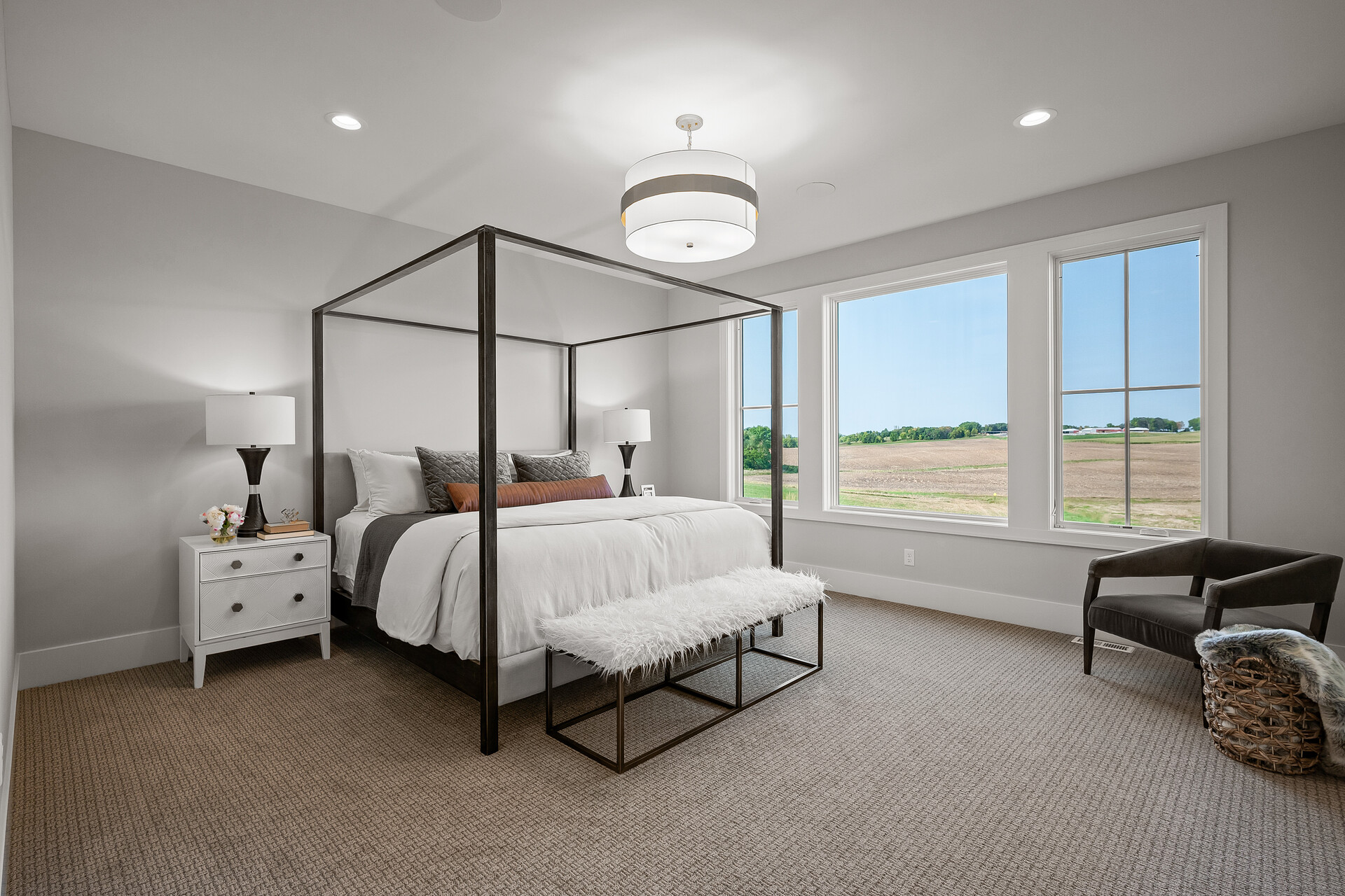 A prairie transitional custom home featuring a bedroom with a four poster bed and a large window.