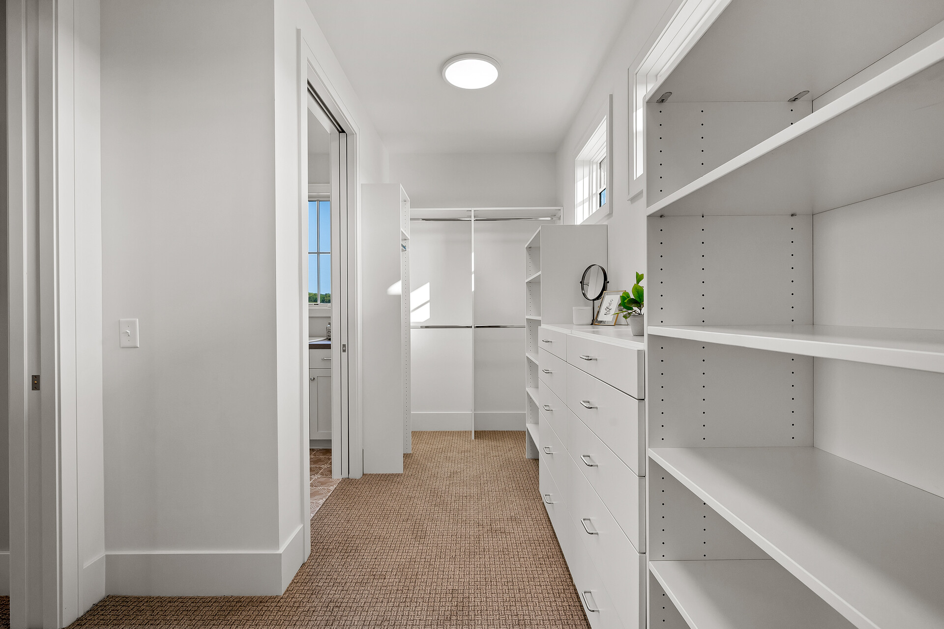 A custom white closet with shelves and a door in a prairie transitional home.