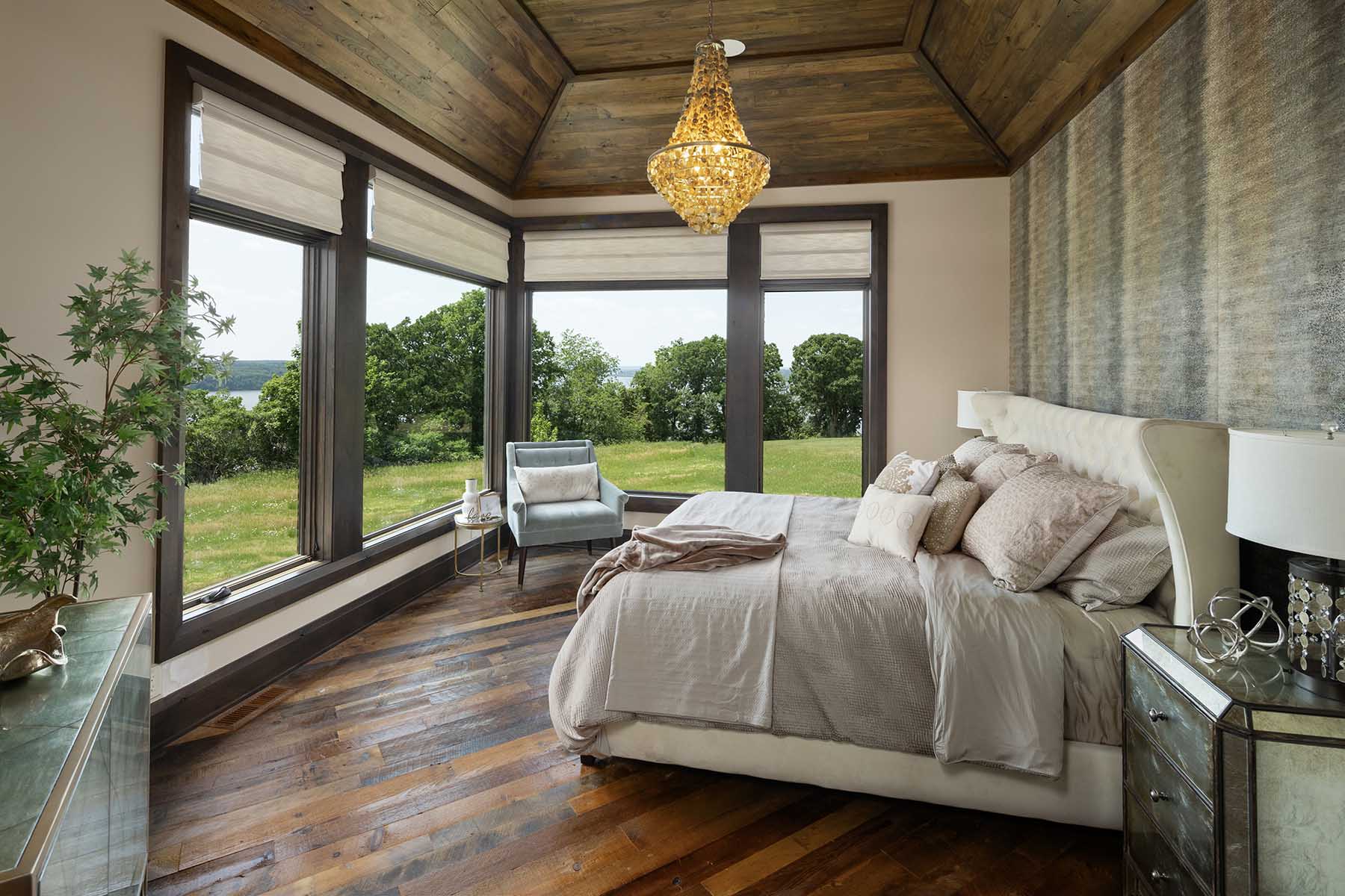 A modern bedroom with wood floors and large windows in a Tuscan Mediterranean home.