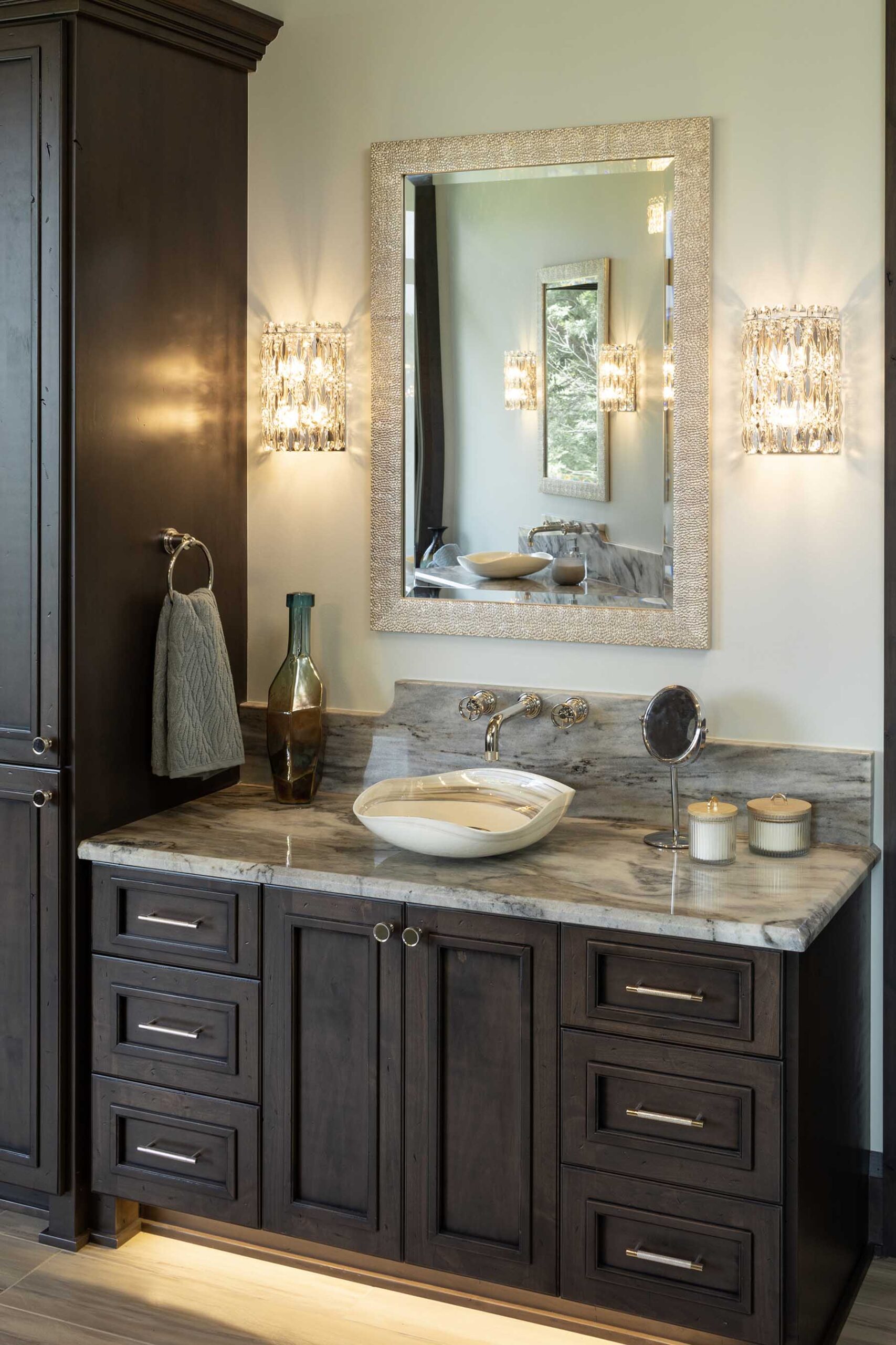 A modern bathroom with dark wood cabinets and a mirror in a Tuscan Mediterranean home.