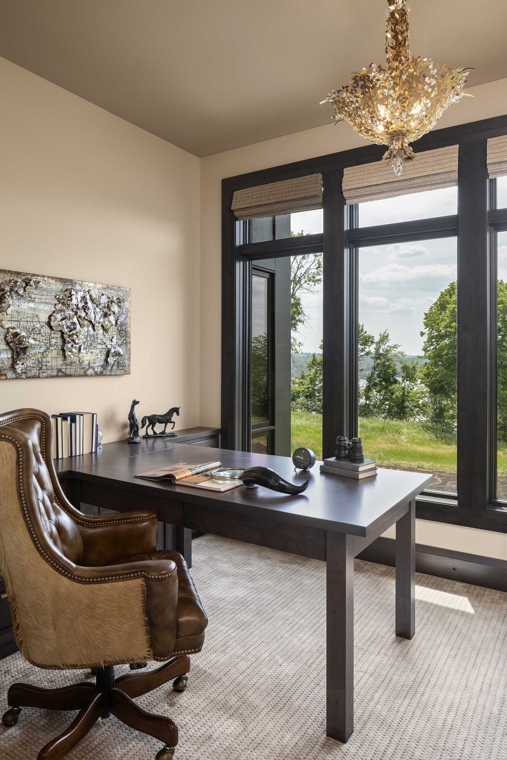 A modern home office with large windows and a leather chair in a Tuscan Mediterranean style.