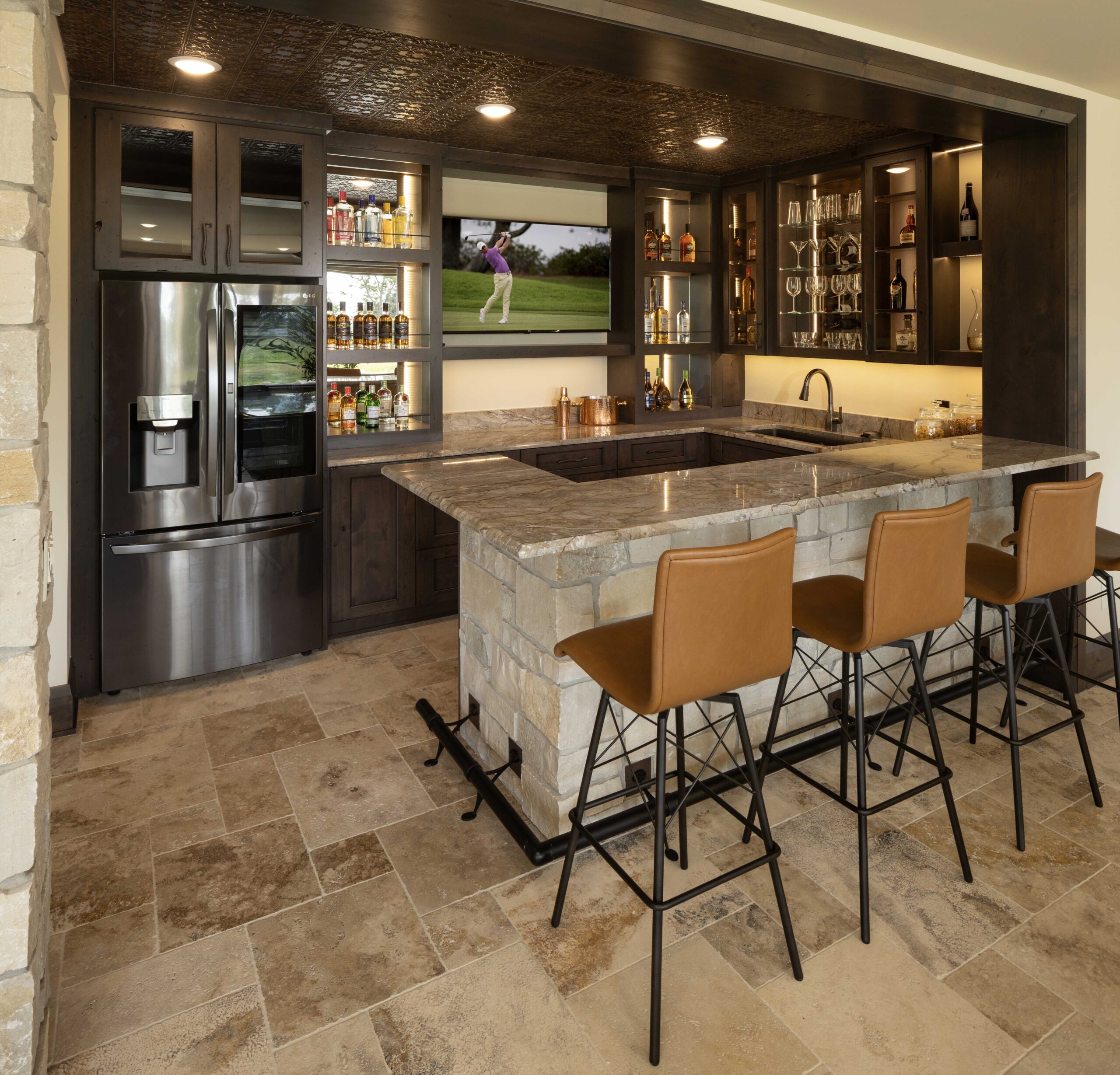 A Modern Tuscan home bar with stools and a television.