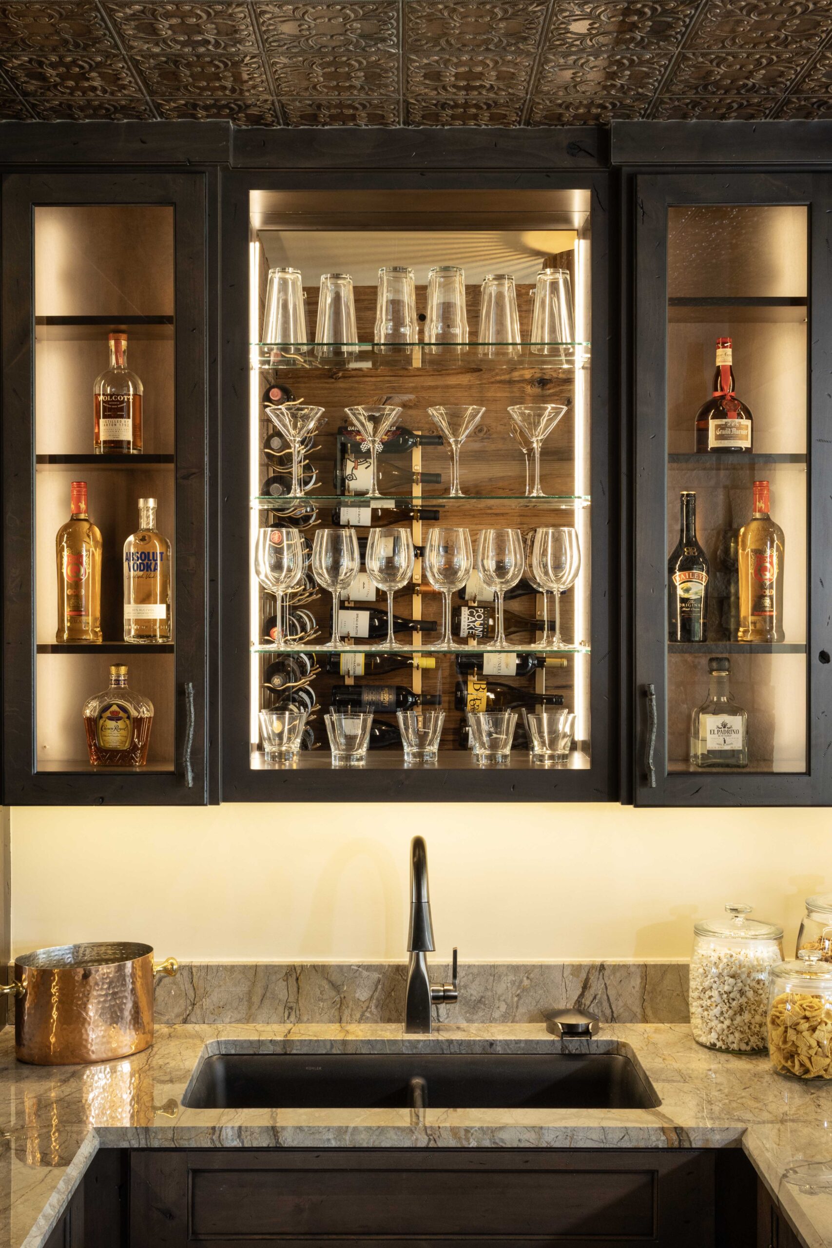 A modern Tuscan bar with a sink and wine glasses in a Mediterranean home.