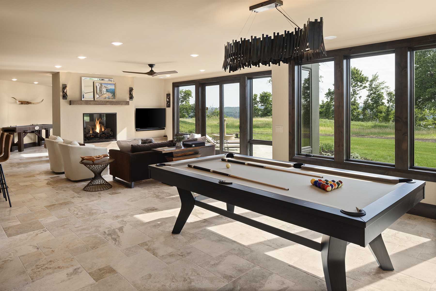 A modern living room with a pool table and a fireplace in a Tuscan Mediterranean home.