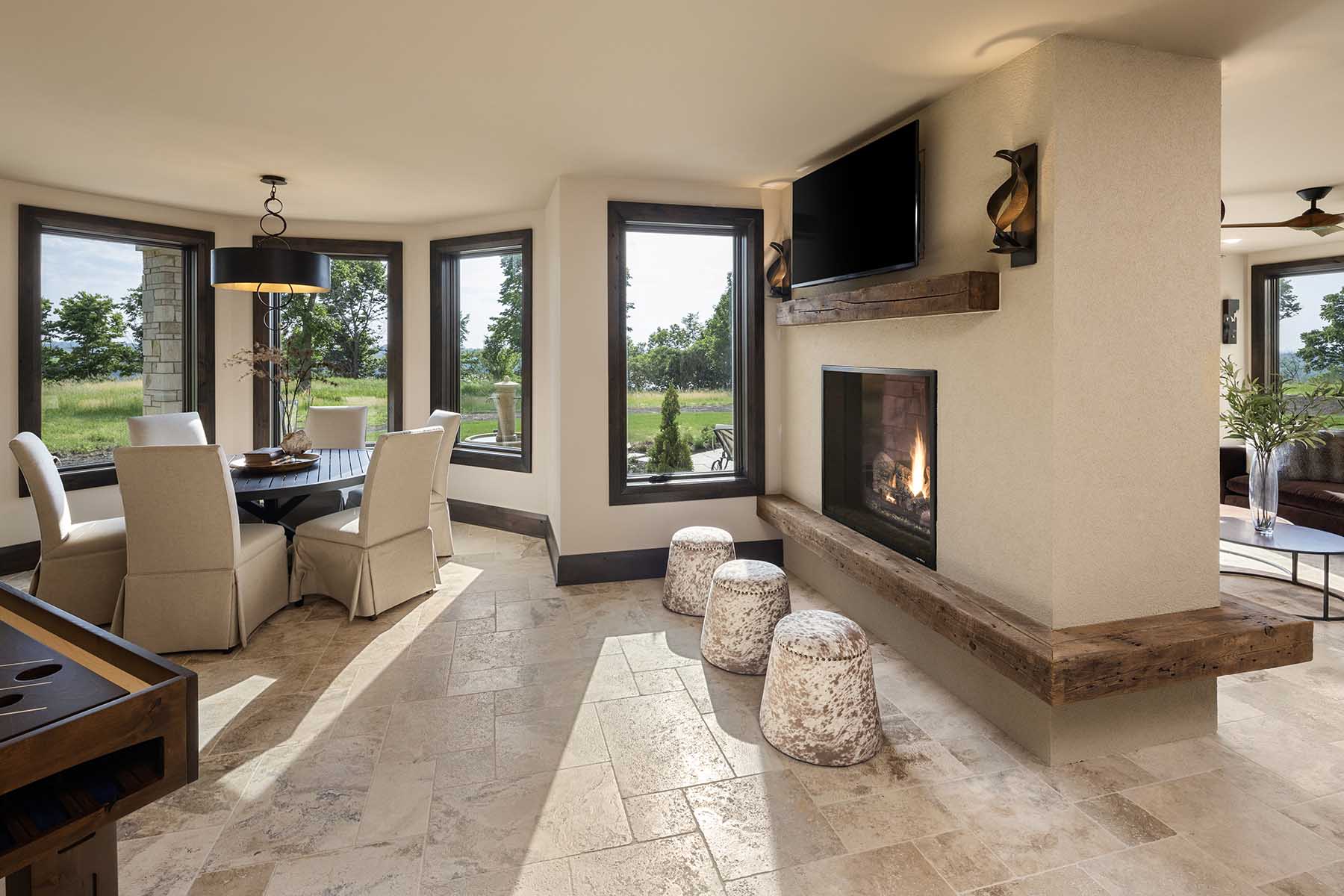 A modern living room with large windows and a fireplace in a Tuscan Mediterranean home.