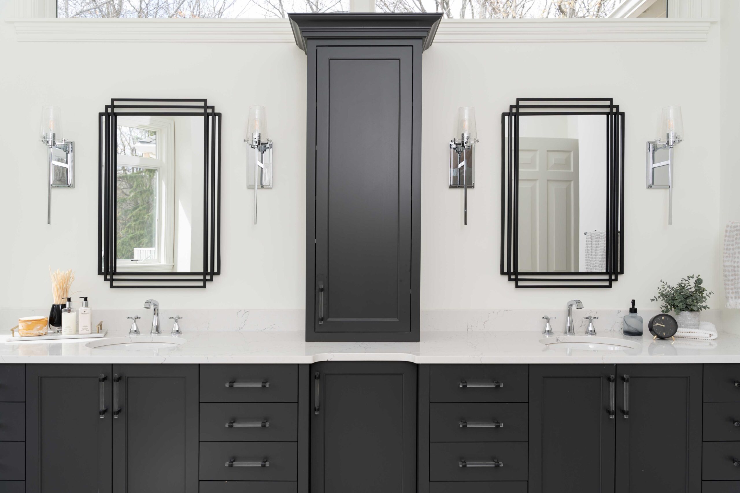 A modern bathroom remodel with black cabinets and mirrors.