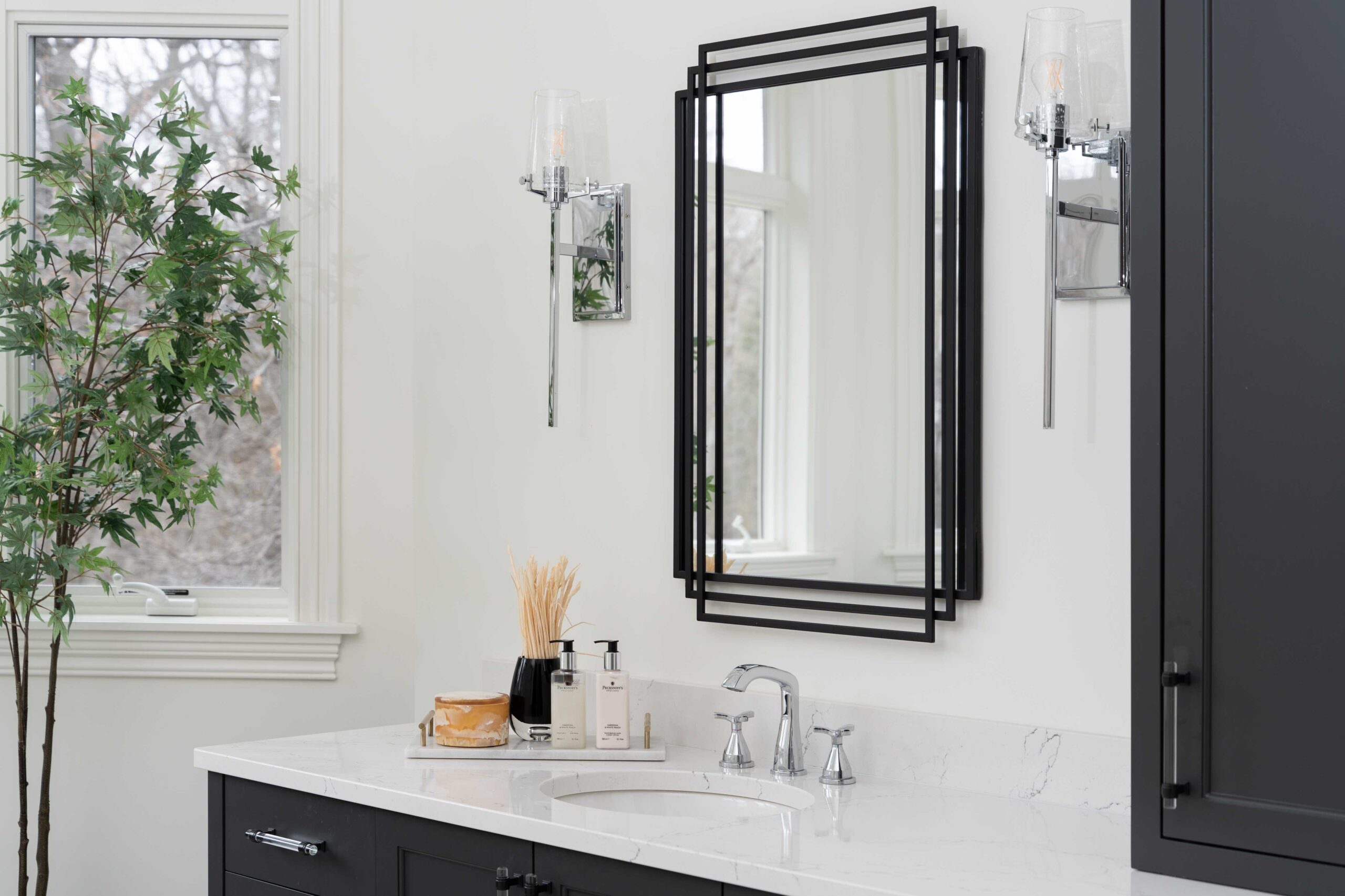 A modern bathroom remodel featuring black cabinets and a mirror.