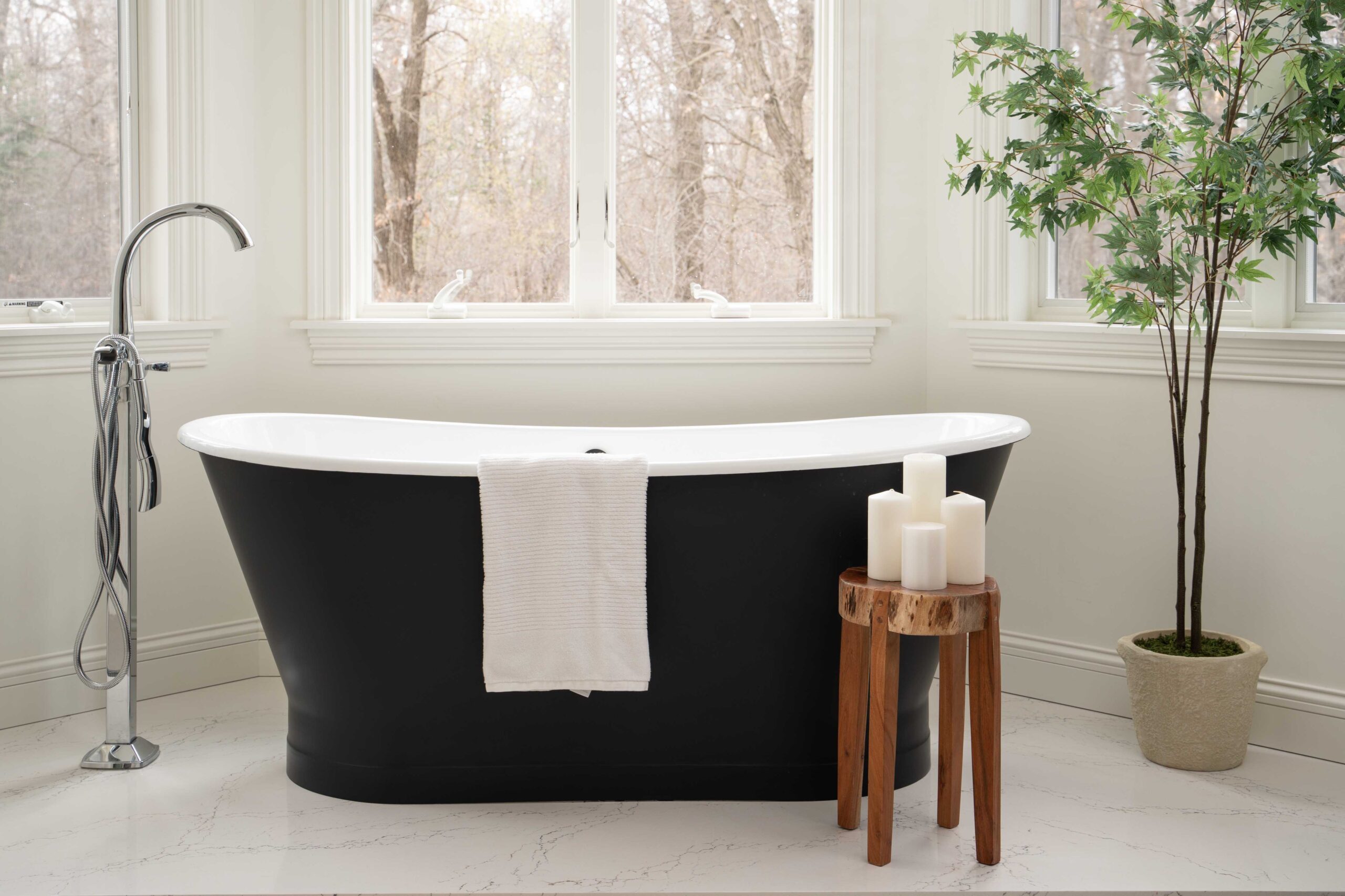 A modern bathroom remodel featuring a black tub and a window for natural light.