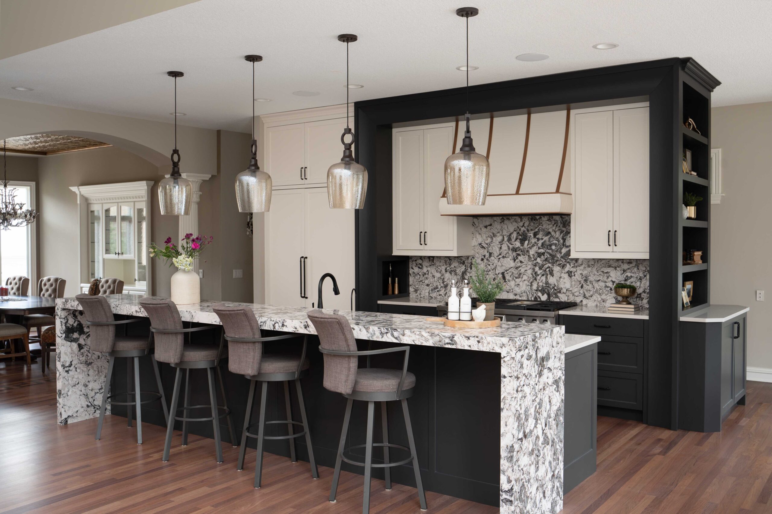 A modern kitchen featuring marble counter tops and bar stools.
