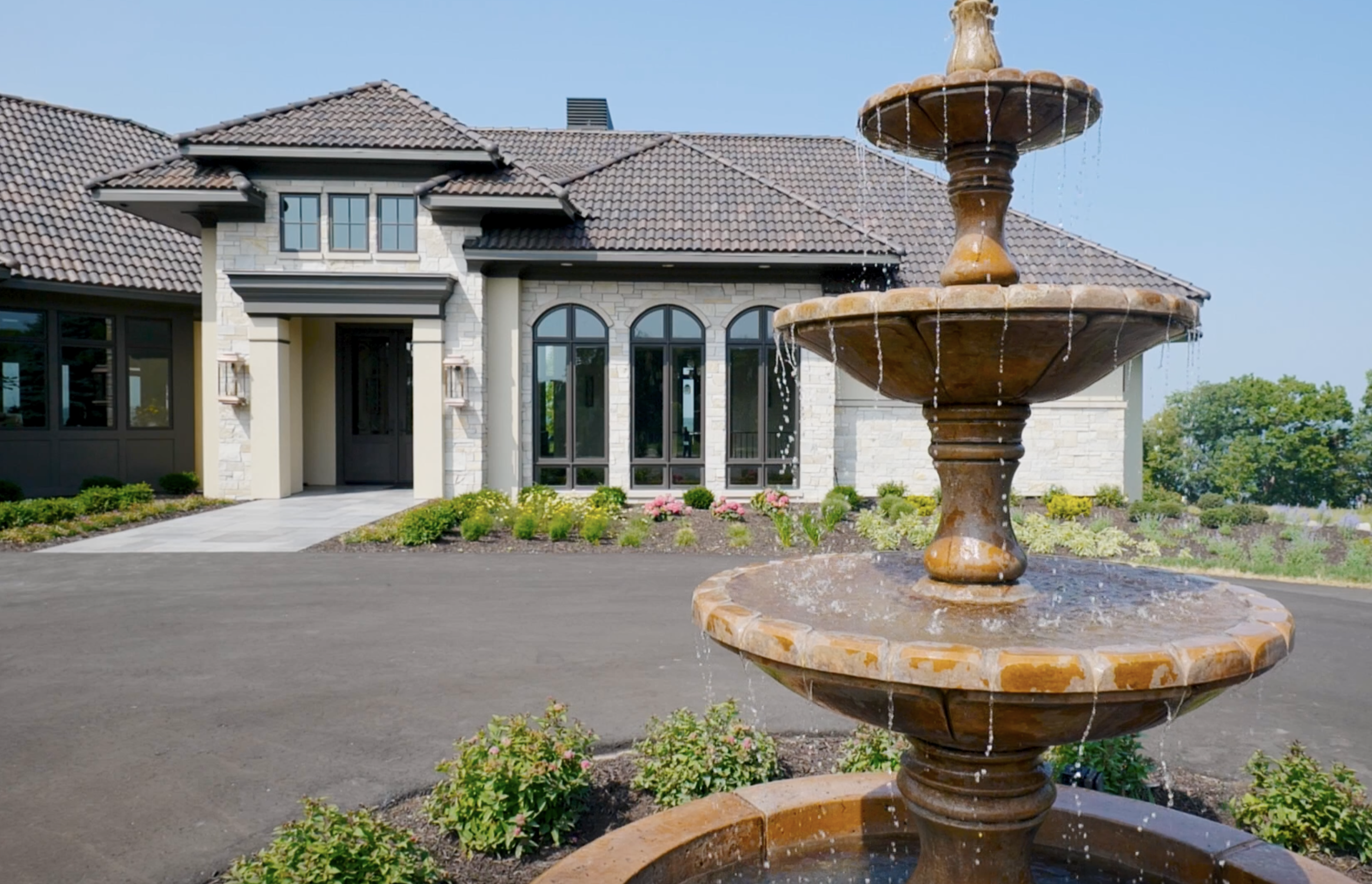 A modern Tuscan Mediterranean home with a fountain in front.