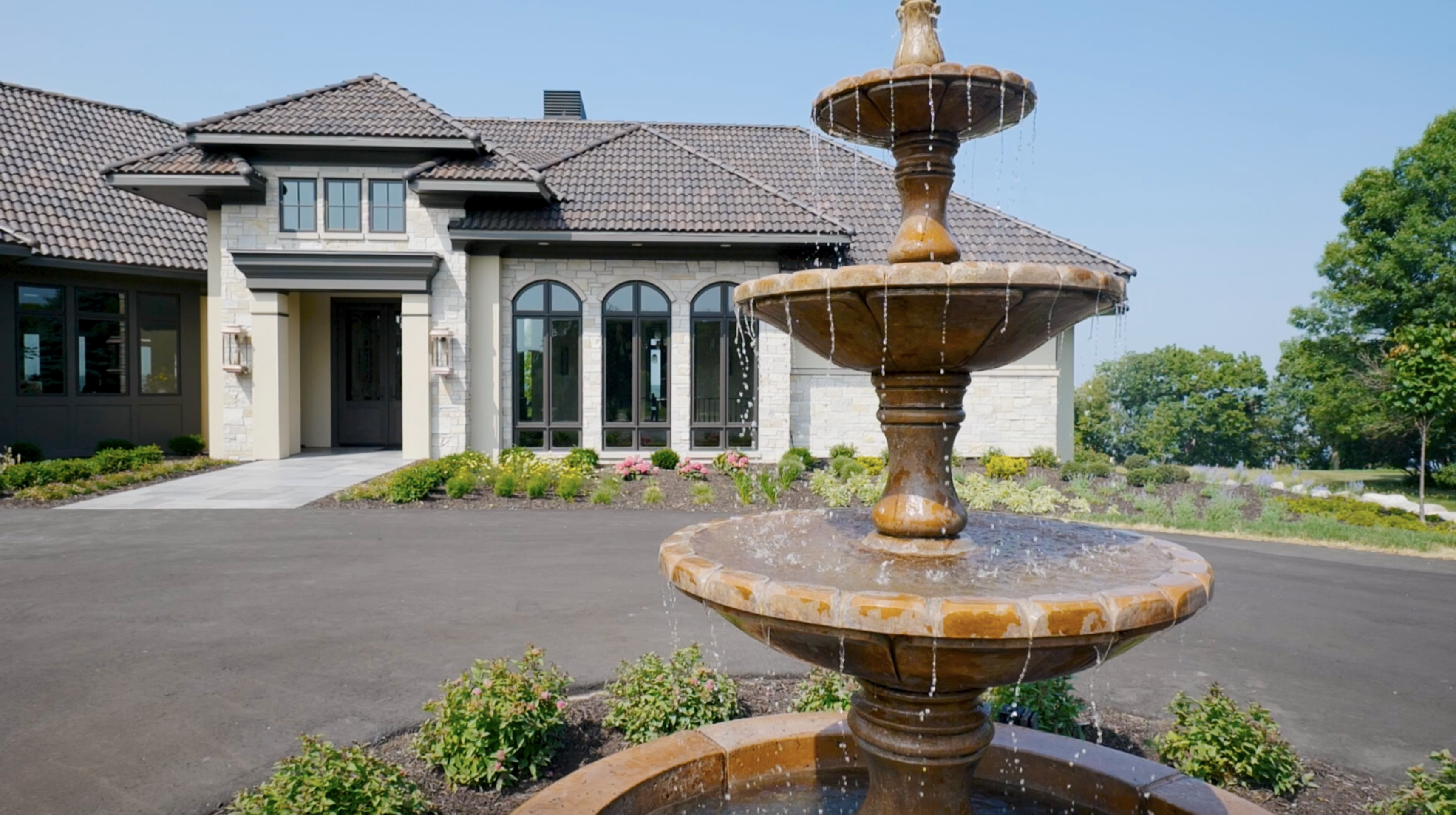 A modern Tuscan Mediterranean home with a fountain in front.