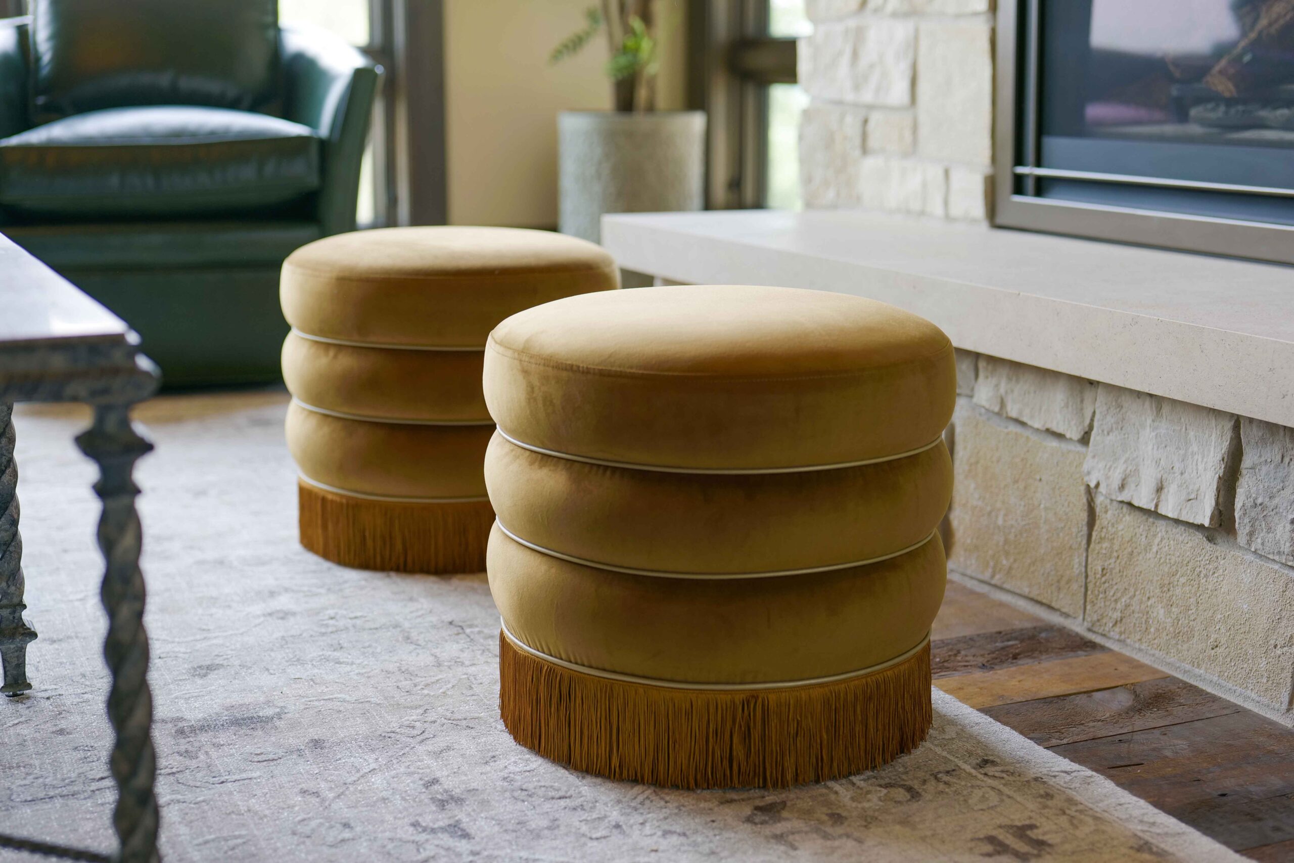 In a Modern Tuscan Mediterranean home, two stools are arranged in front of a fireplace in the cozy living room.