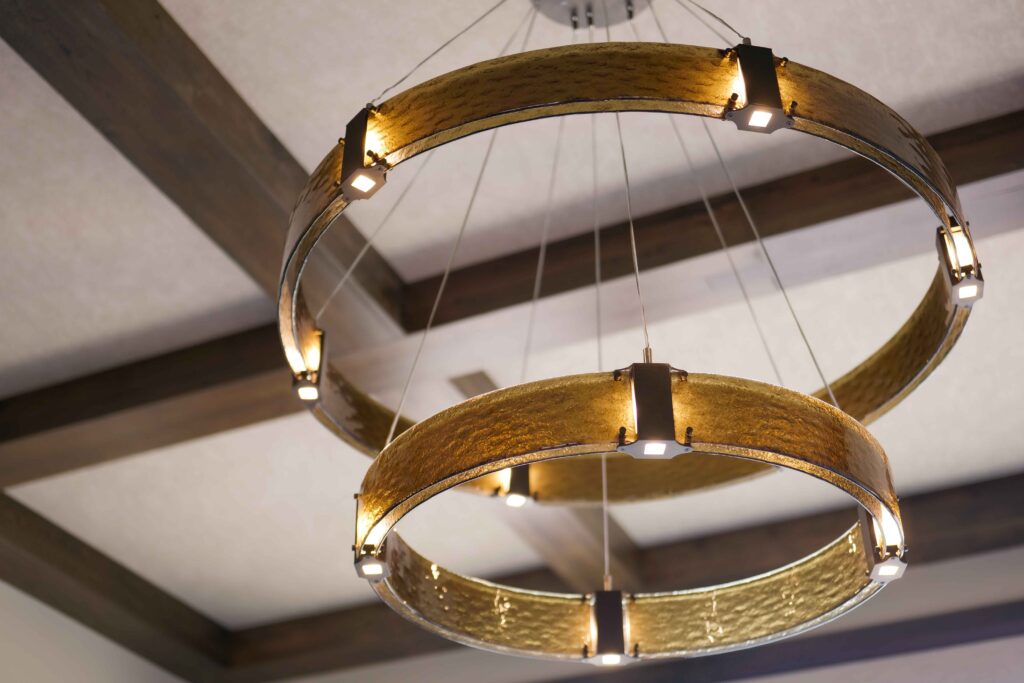 A modern chandelier with a circular shape hanging from the ceiling in a Tuscan home.