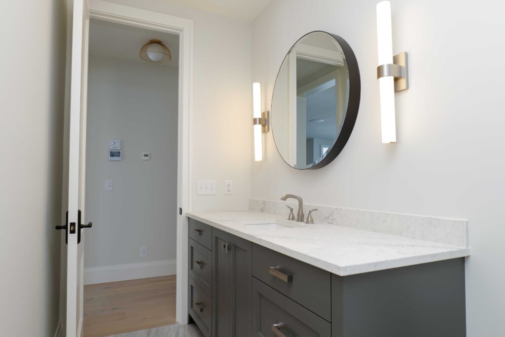 A bathroom with a gray vanity and mirror.
