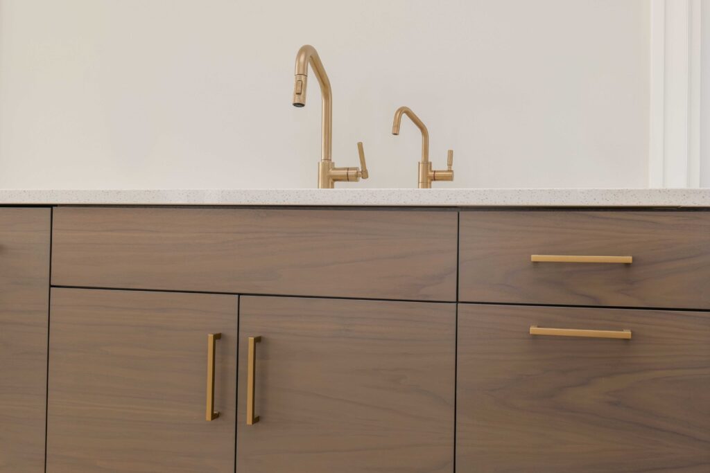 A kitchen with wooden cabinets and brass faucets.