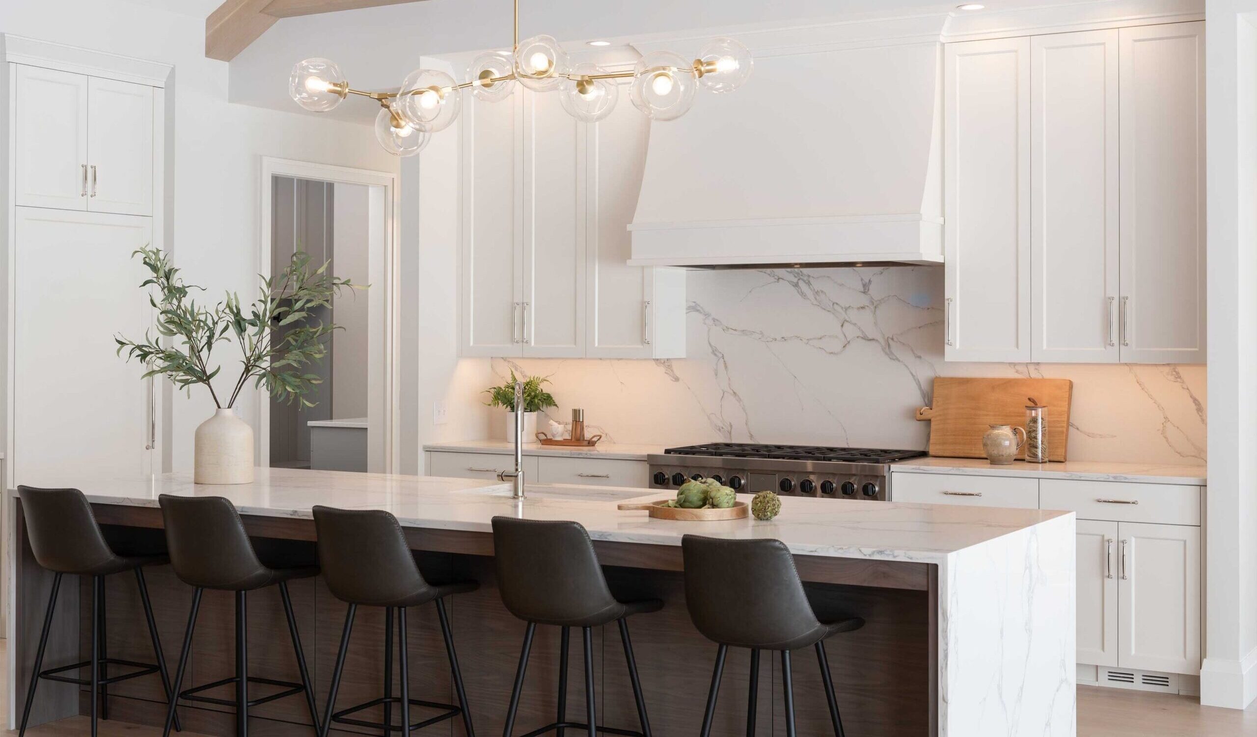 A modern kitchen with white cabinets and black stools.