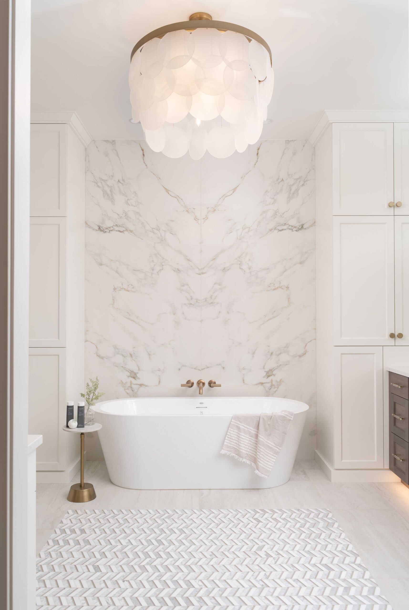 A white bathroom with marble floors and a chandelier.
