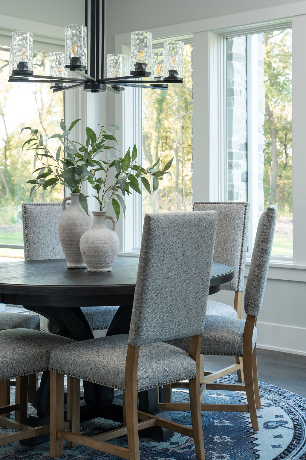 A transitional dining room with a round table and farmhouse chairs.