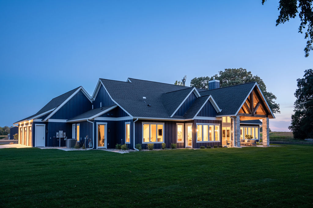 A Transitional Farmhouse home with a blue exterior at dusk.
