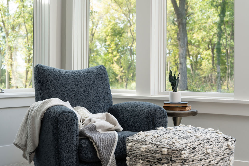 A blue chair and ottoman in front of a window, blending transitional farmhouse style.