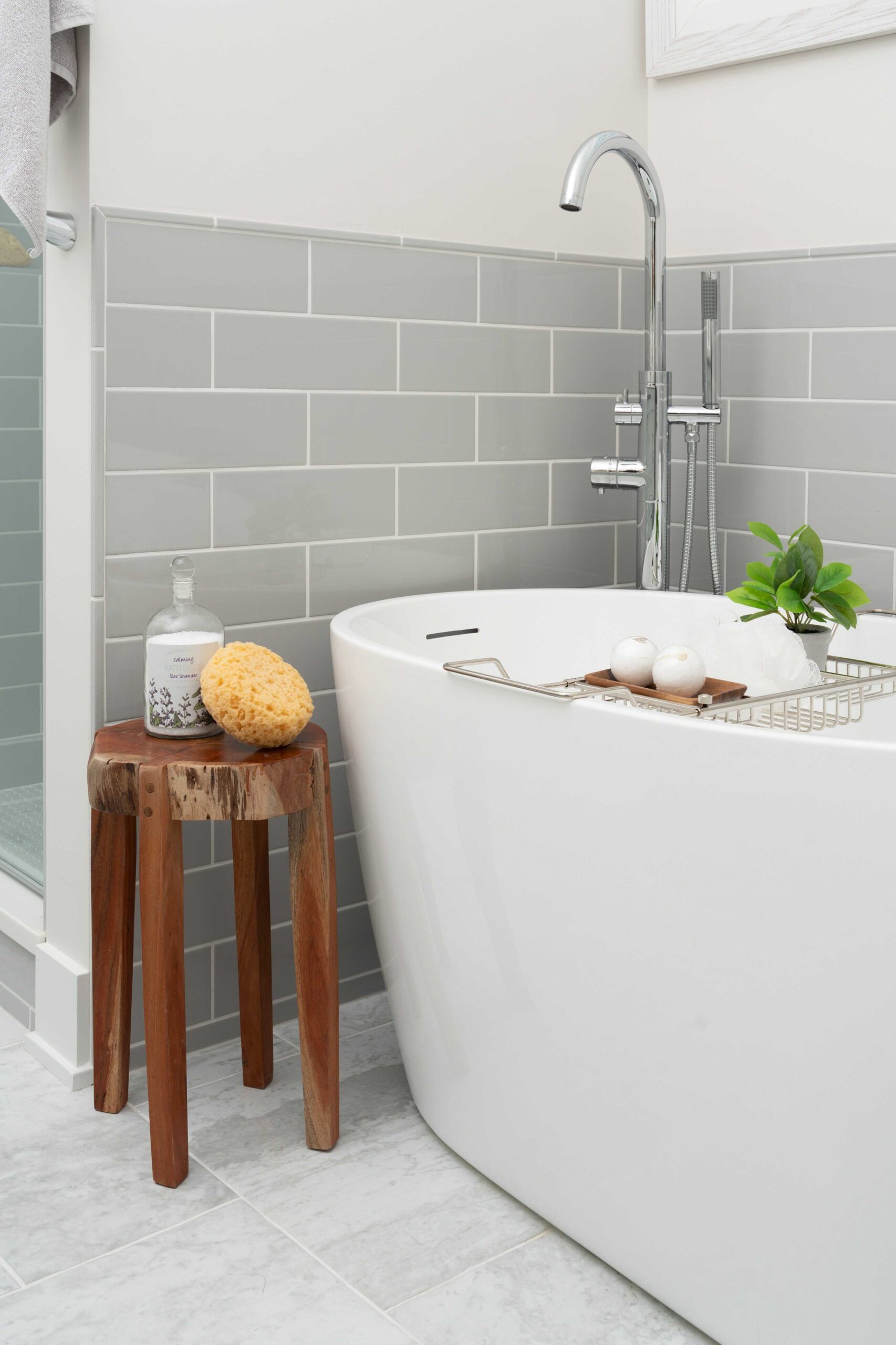 A bathroom with a white tub and wooden stool in the Orchard Lake Remodel.