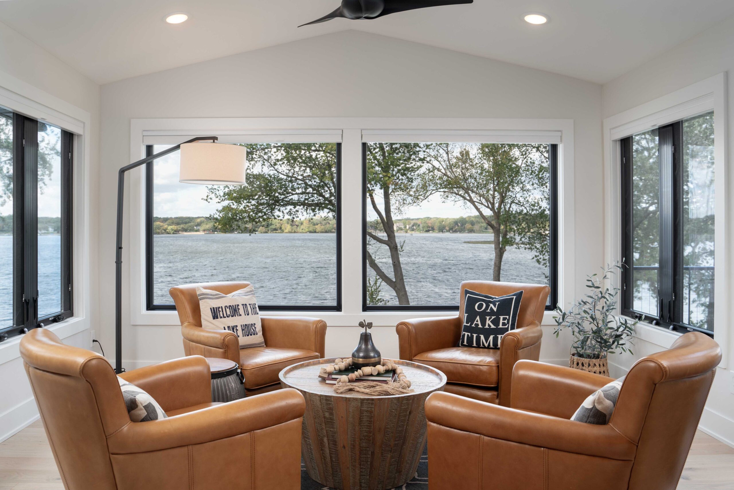 This Orchard Lake Remodel features a inviting living room with luxurious leather chairs and stunning views of the lake.
