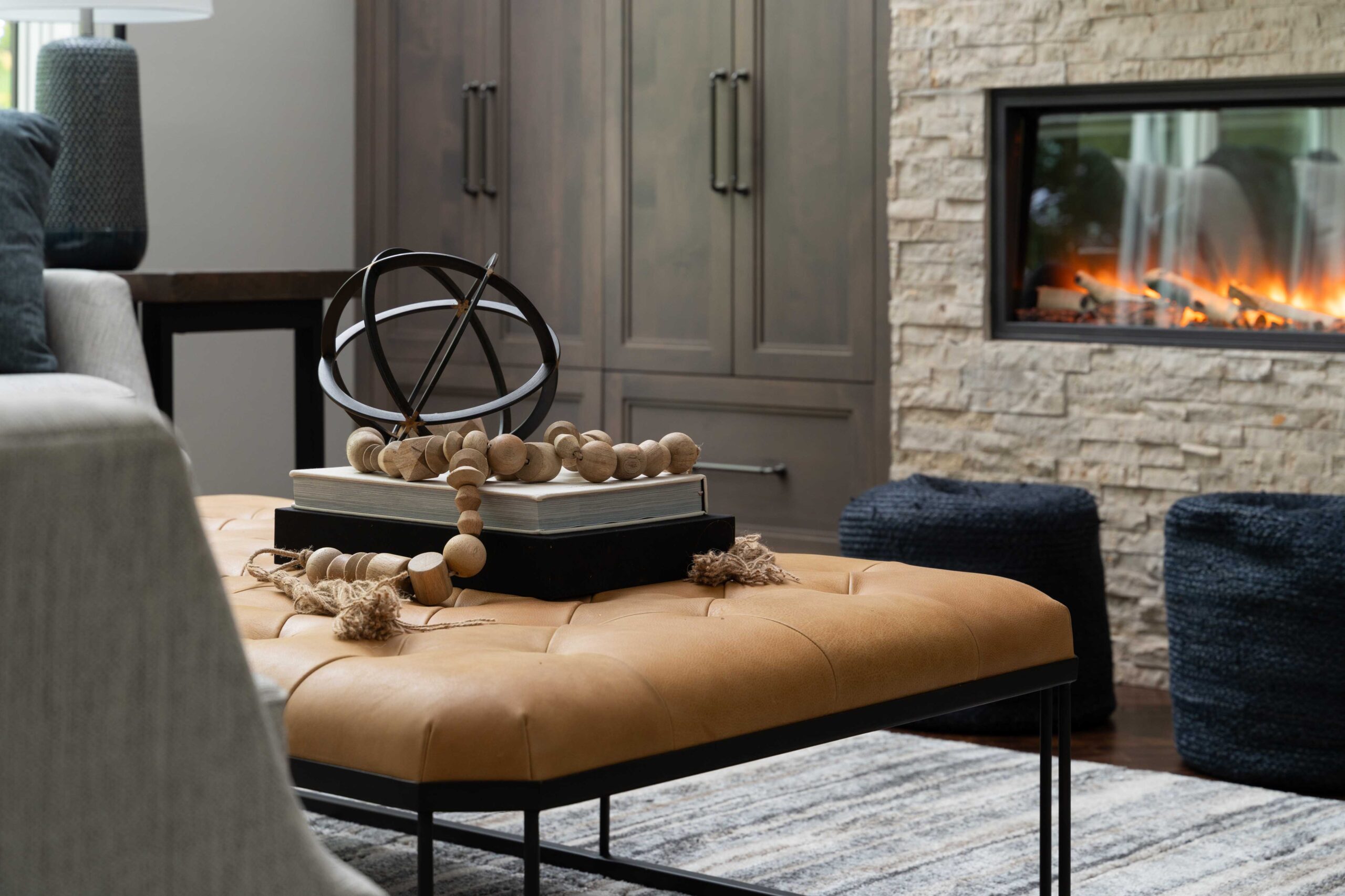 Great Waters Alcove Remodel: A living room with a stone fireplace and ottoman.