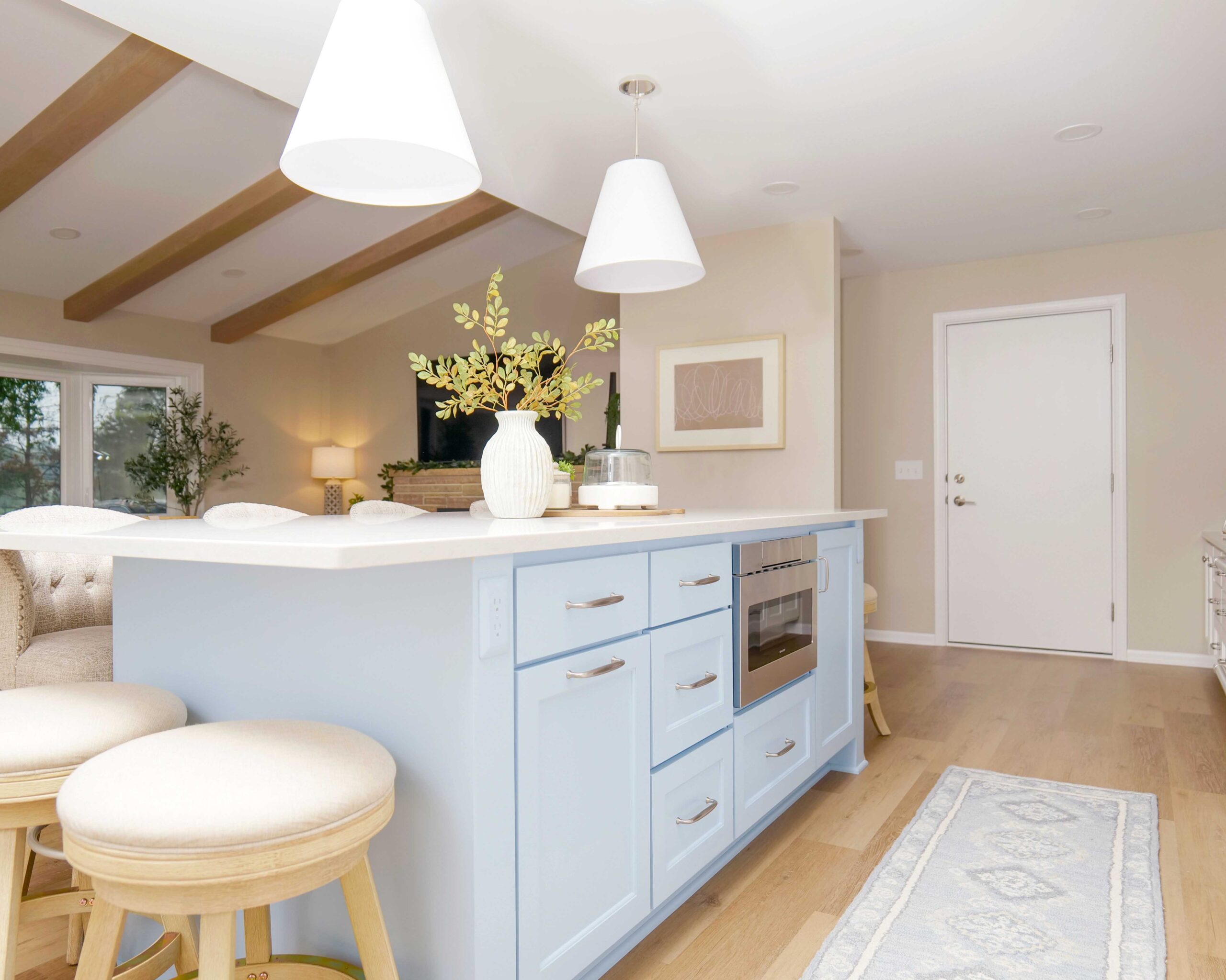 A coastal style kitchen remodel with a blue island and stools.