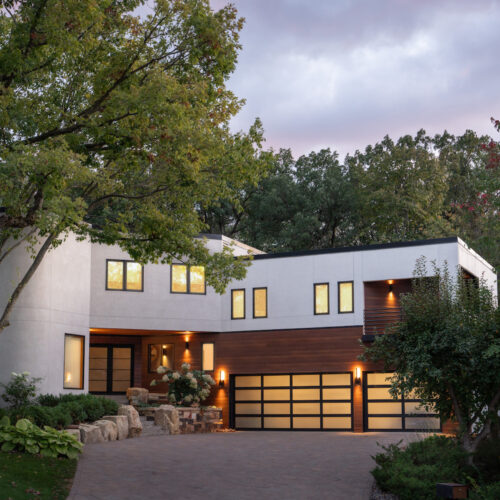 A modern home with a driveway and trees.