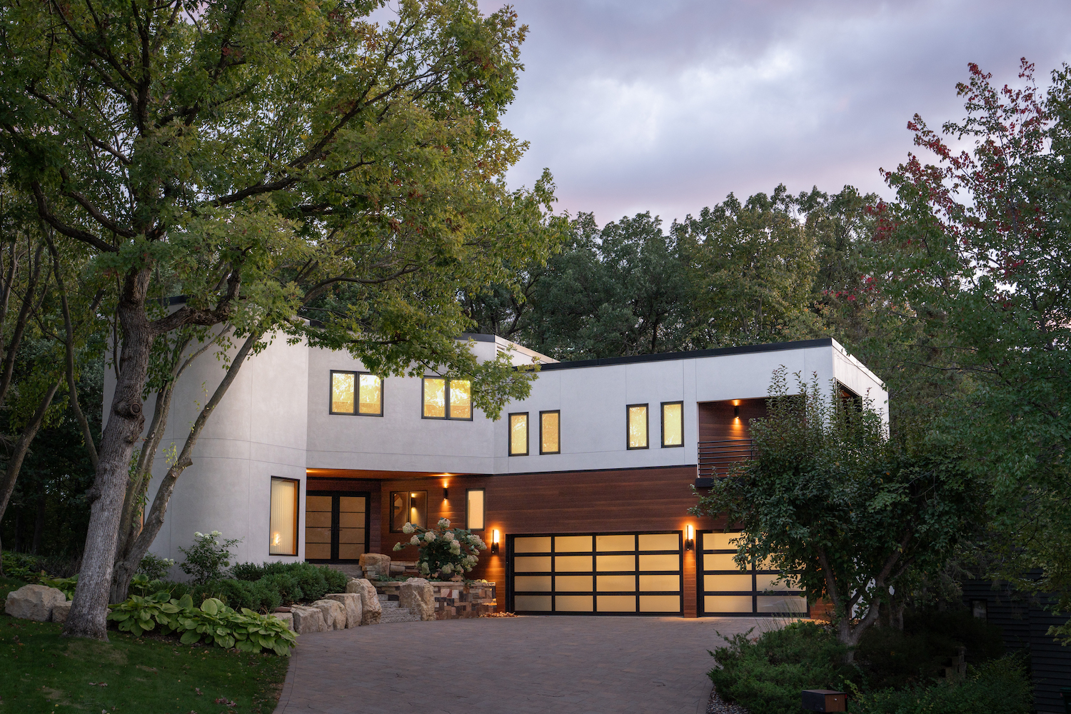 A modern home with a driveway and trees.