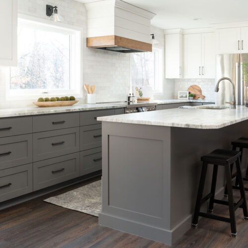 A modern cottage kitchen with white cabinets and gray countertops.