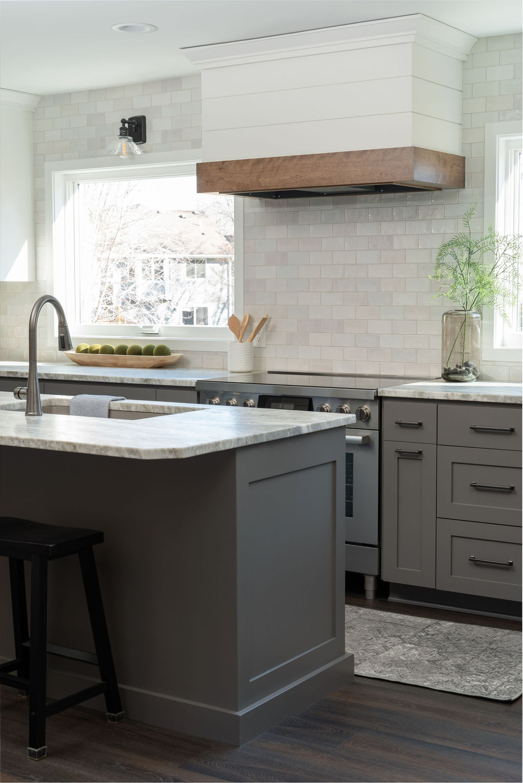 A modern gray kitchen with a white island and stools.
