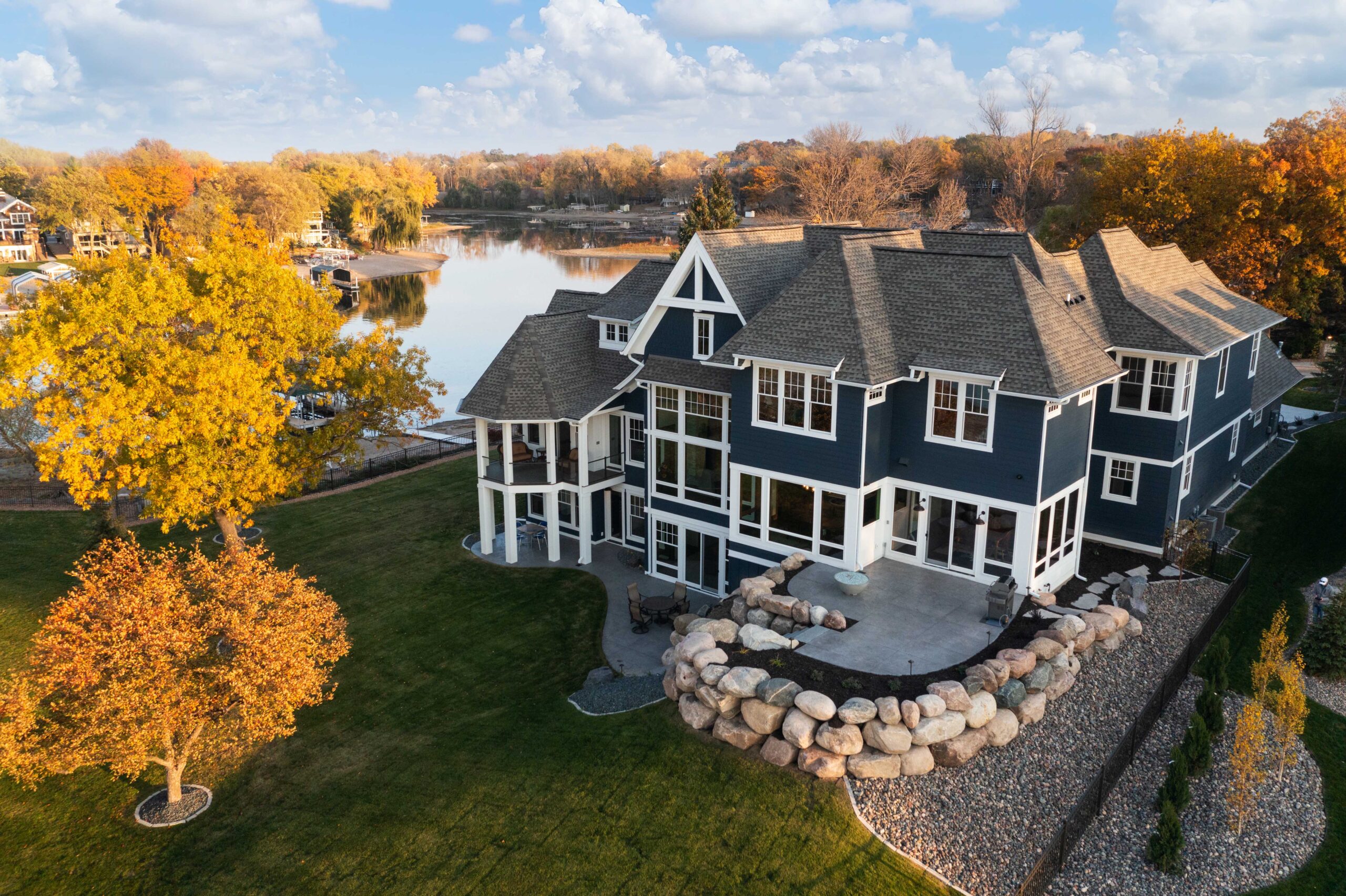 An aerial view of a modern home with a lake in the background.