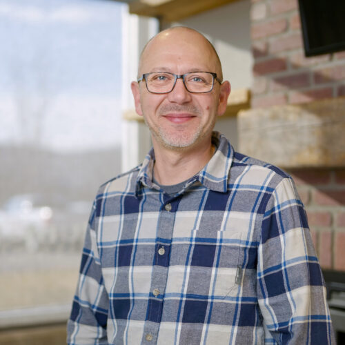 A man wearing glasses and a plaid shirt, about Highmark Builders.