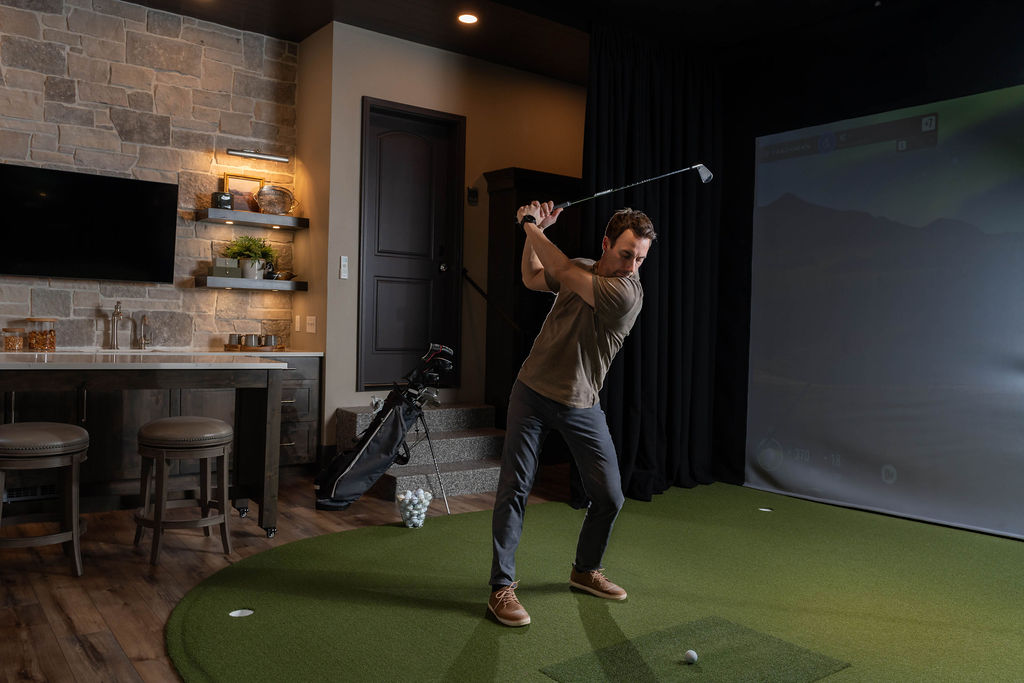 Man practicing golf swing in newly remodeled indoor golf simulator and bar.